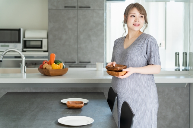 写真素材：ダイニングで食事の用意・配膳をする妊婦
