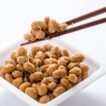 大粒の納豆パック。納豆を箸で持ち上げる。